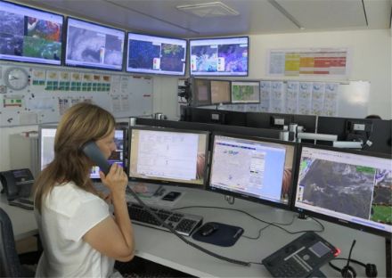Fig. 2: Una postazione di lavoro in sala previsioni a Locarno-Monti. Sullo sfondo le schermate alla parete con diverse visualizzazioni dei dati provenienti da NinJo.