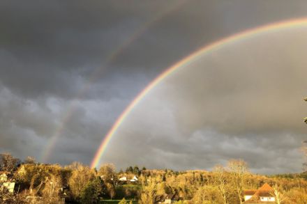 Doppio arcobaleno con nubi nere sullo sfondo.