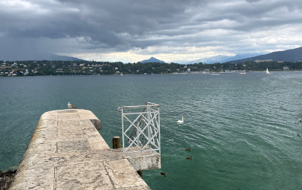 Lago Lemano con muro di protezione del porto e nubi cupe sullo sfondo.