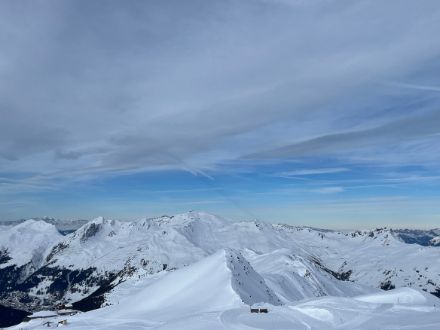 Foto panoramica di montagne, al di sopra vasti campi nuvolosi, sullo sfondo cielo azzurro.