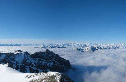 Panorama con nebbia alta e montagne innevate sullo sfondo.