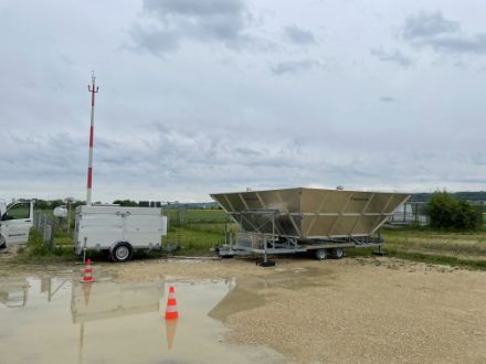 Figura 1: Il profilatore radar mobile del vento installato a Grenchen accanto alla stazione SwissMetNet (rete di monitoraggio automatico al suolo). Il piccolo rimorchio sulla sinistra ospita l'elettronica per la registrazione e la trasmissione dei dati di misura. Il profilatore radar fisso, che deve essere sostituito, è visibile sulla destra dietro il radar mobile.