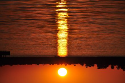 Immagine capovolta del riflesso del sole sul mare, che appare come una colonna di luce.