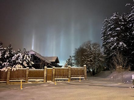 Pilasti di luce nel cielo sopra un paesaggio innevato.