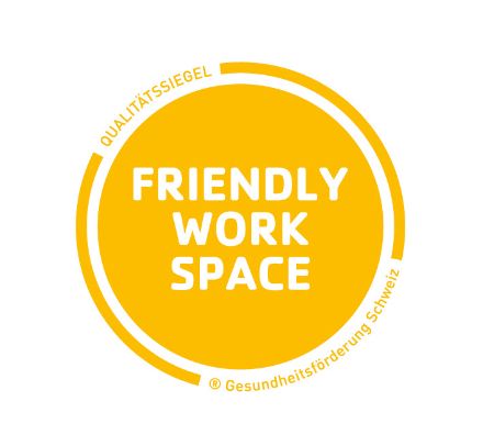 Das Logo des Friendly Workspace Label setzt sich auf einem gelben Kreis zusammen. In der Mitte steht in weisser Schrift Friendly Work Space und am Rand, dass es sich um ein Qualitätssiegel der Gesundheitsförderung Schweiz handelt. 