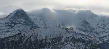 Eiger, Mönch e Jungfrau visti dalla Schynige Platte durante un evento di Guggiföhn. Sull'immagine ripresa da una webcam è ben visibile il muro del favonio. In primo piano, sul Lauberhorn, sono visibili dei pennacchi di neve ventata.