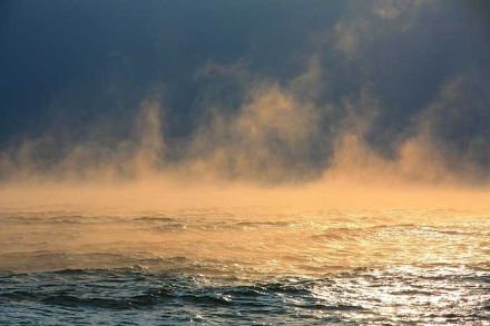 Nebbia da evaporazione sopra un lago, che brillando alla luce del Sole assume un colore arancione.