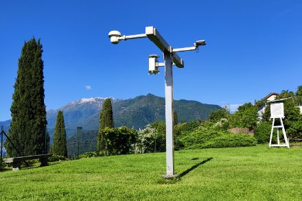 Ponte di misura a 2m dal suolo presso la stazione SwissMetNet di Locarno Monti, verso sud due termoigrometri, a nord un rilevatore di precipitazione. Sullo sfondo a destra la classica capannina Stevenson.