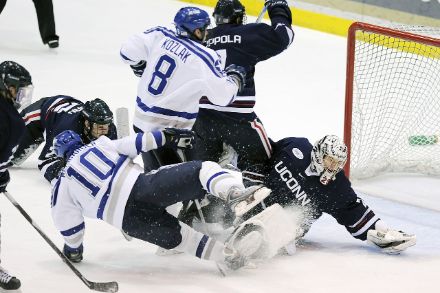Immagine da una partita di hockey con giocatori che lottano per il possesso del disco. 