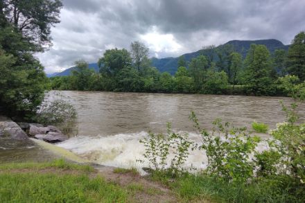 Fiume in piena, con acqua color marrone e cielo coperto di nuvole.